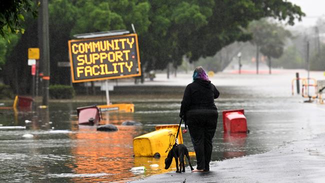 A woman walks her dog on a flooded road in Lismore in March. Picture: Getty Images