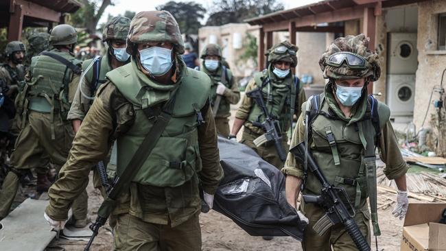 Israeli soldiers remove a body from Kfar Aza.