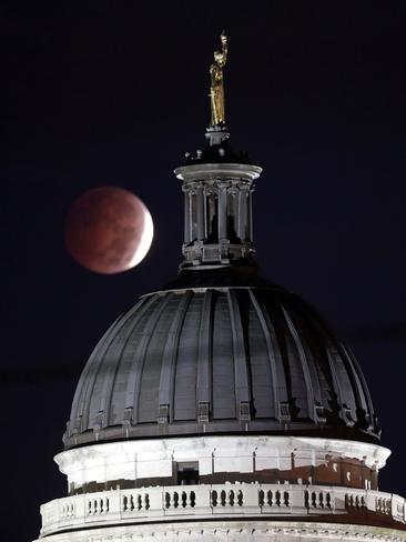 A lunar eclipse is seen near a statue entitled “Enlightenment Giving Power” by John Gelert, which sits at the top of the dome of the Bergen County Courthouse in Hackensack, N.J. Picture: AP