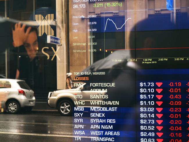 A man is seen in a reflection to stop to look at the electronic share board at the Australian Stock Exchange (ASX) in Sydney, Monday, Aug. 24, 2015. The ASX 200 has dipped below 5100 points for the first time in 18 months, as the big banks continue to bear the brunt of fear selling and with the big miners also getting hit on continued weakness in commodity prices. (AAP Image/Dan Himbrechts) NO ARCHIVING