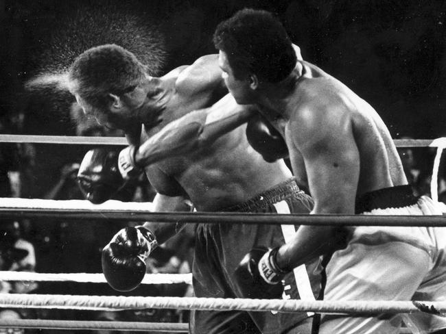 Perspiration flies from the head of defending heavyweight champion boxer George Foreman as he takes a right from challenger Muhammad Ali