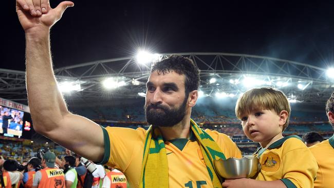 Australia's Mile Jedinak acknowledeges the crowd as he carries his son.