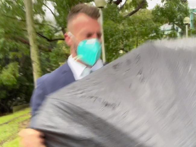James Olsson, 45, of Avoca Beach, hid behind his lawyer's umbrella as he left court after an earlier appearance. Picture: NewsLocal
