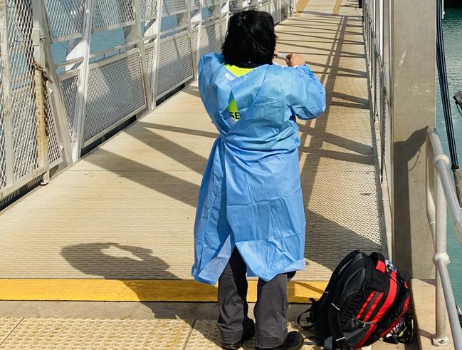 Covid-19. A member of the Northern Territory Health Department gets dressed into full Personal Protect Equipment before boarding a small yacht which arrived at Cullen Bay from Indonesia. Picture Gary Shipway