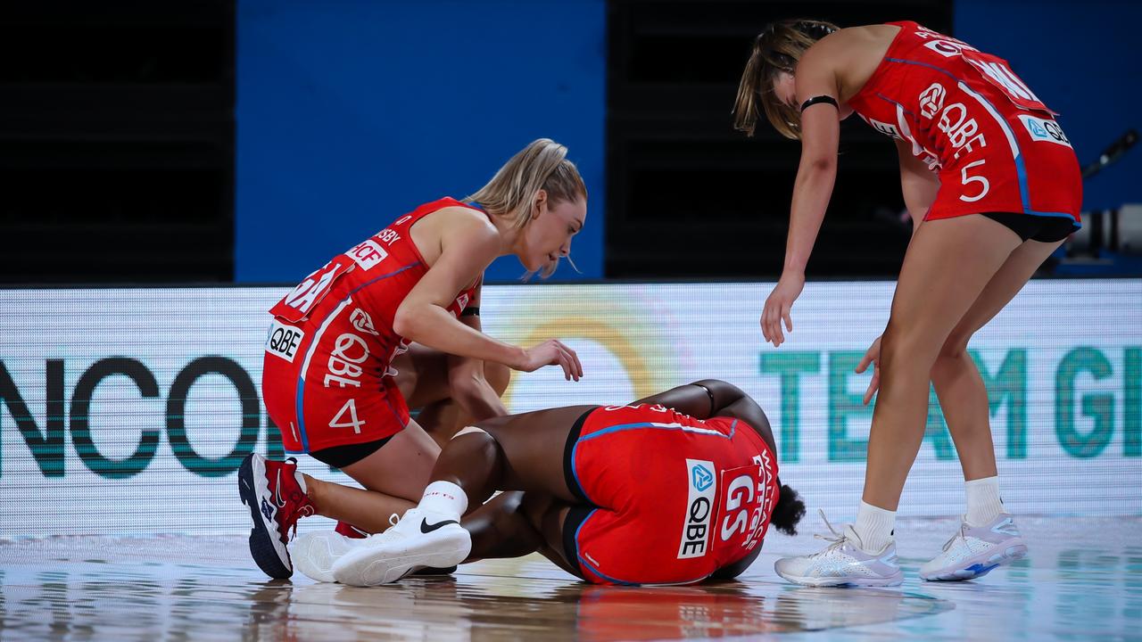 Helen Housby (left) and Maddy Proud (right) come to the aid of Sam Wallace after she crashed to the court following a devastating knee injury. Photo: Narelle Spangher, Netball NSW