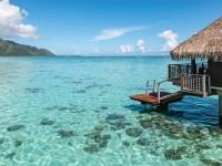 Beautiful travel image with turquoise colored lagoon at the beach with over water bungalow or luxury over water villa on a summer vacation day. French Polynesia, Tahiti, Moorea, Bora Bora.