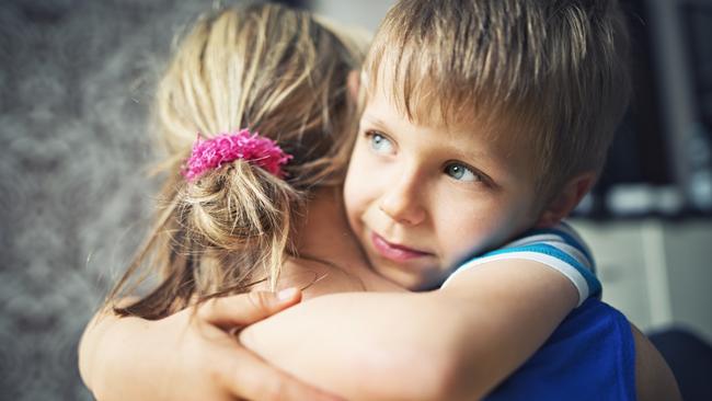 Closeup of happy little boy aged 5 embracing his mother. The mother and boy are lit by soft light from the window.