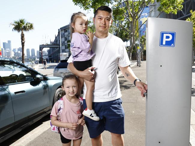 Adam Lung, with his daughters Matilda and Charlotte, feeds the meter. Picture: Richard Dobson