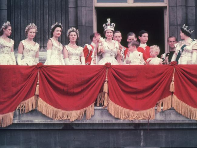 The newly crowned Queen Elizabeth II waves to the crowd from the balcony at Buckingham Palace. Her children Prince Charles and Princess Anne stand with her.