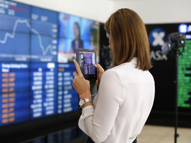 A woman uses a tablet device to take a photograph of an electronic board displaying stock information inside the Australian Securities Exchange, operated by ASX Ltd., in Sydney, Australia, on Thursday, Nov. 10, 2016. Stocks in Asia rebounded from their steepest slide since Brexit, industrial metals surged and regional bonds tumbled after Donald Trump's election victory and spending pledges spurred gains in U.S. shares. Photographer: David Moir/Bloomberg