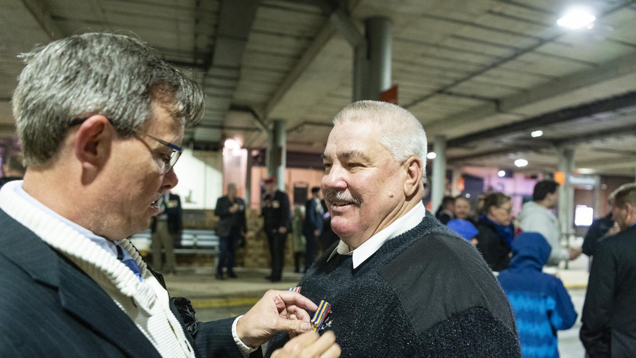 Brian Alderton (left) helps Peter Yarrow pin his and his fathers medals before the Anzac Day dawn service, Monday, April 25, 2022. Picture: Kevin Farmer