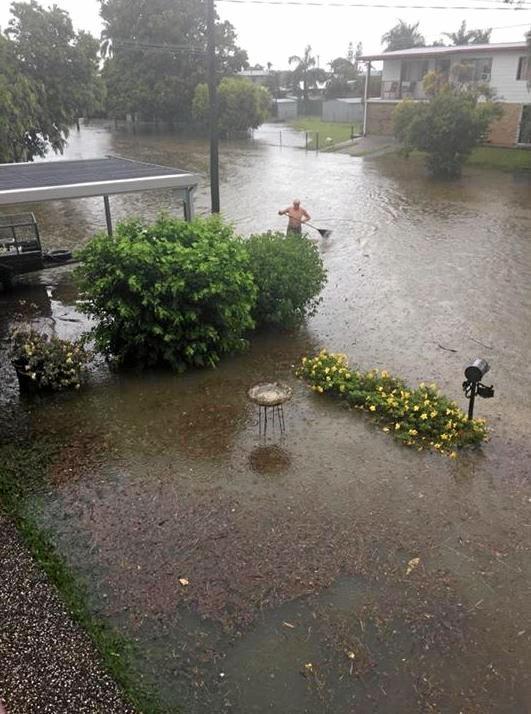 A man is seen with a rake in the floodwaters on Wackford St in Park Avenue. Picture: Taylor Davies