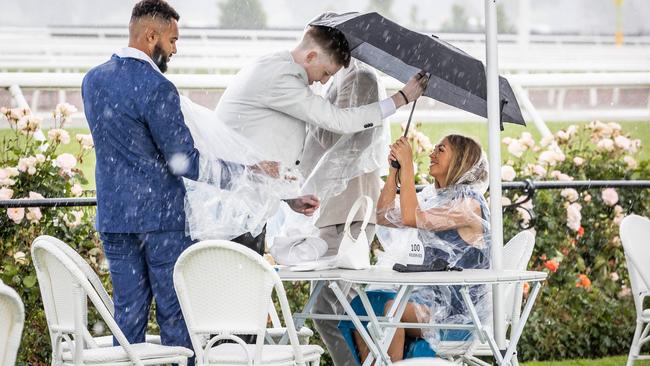 Punters shelter from the rain. Picture: Jake Nowakowski