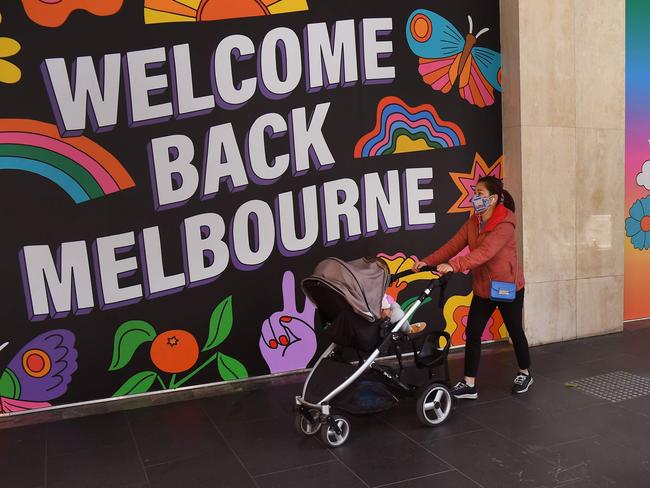 People walk past signs after measures to curb the spread of the Covid-19 coronavirus were eased allowing limited numbers of people back into shops, bars, cafes and restaurants in Melbourne on October 28, 2020. (Photo by William WEST / AFP)