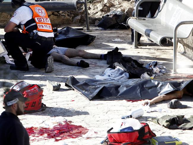 An Israeli medic inspects the body of a Palestinian at the scene of a shooting attack near the Damascus gate, Jerusalem's Old City, Wednesday, Feb. 3, 2016. Three Palestinians carrying automatic weapons, explosive devices and knives shot and stabbed two Israeli security officers in Jerusalem on Wednesday, wounding both before police shot and killed the attackers, police said. (AP Photo/Mahmoud Illean)