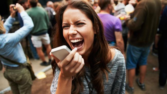 A pretty young woman shouting into her smartphone at an outdoor music festival Picture i stock image