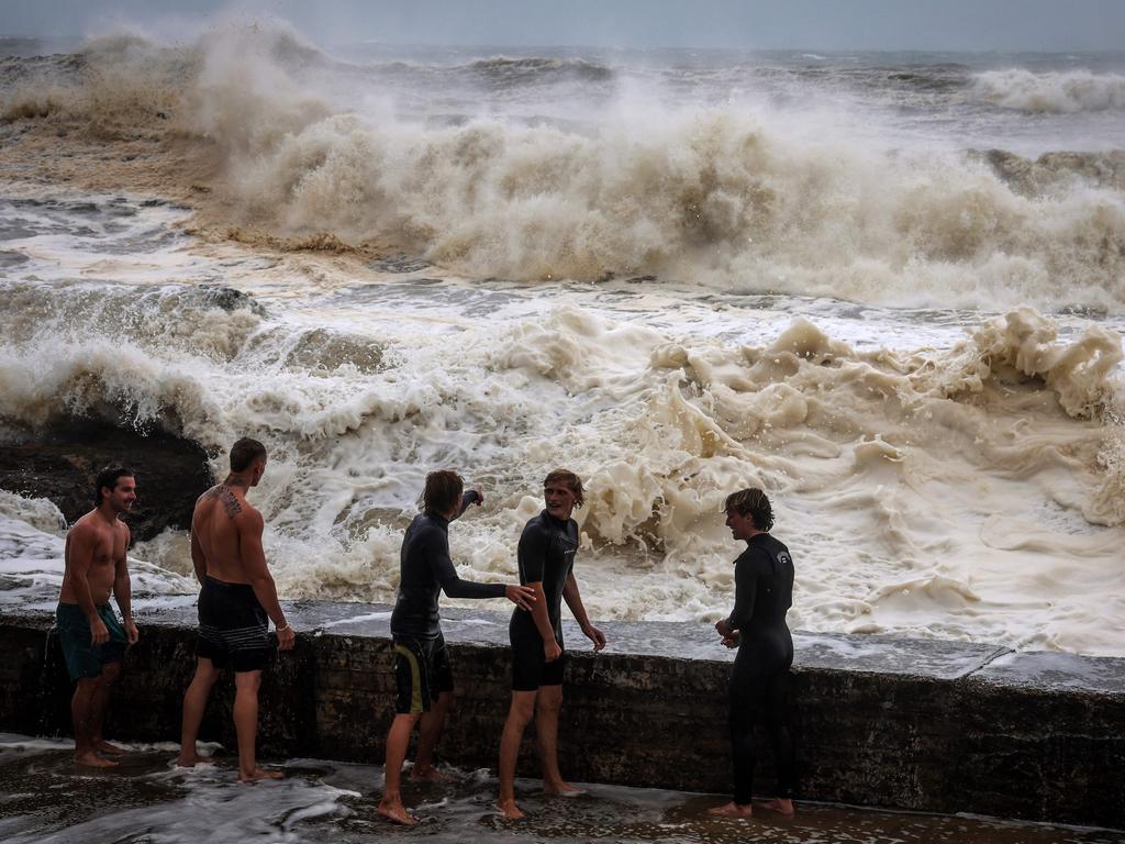 Young men stand behind a wall as they play in record-breaking waves at Coolangatta. Picture: David Gray