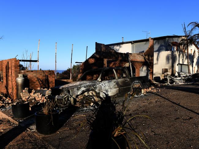 Some of the more than 70 houses and businesses destroyed by a bushfire in the coastal town of Tathra, Monday, March 19, 2018. RFS and NSW Fire and Rescue continue to mop up and douse smouldering homes after a devastating fire ripped through the community yesterday and overnight. (AAP Image/Dean Lewins) NO ARCHIVING