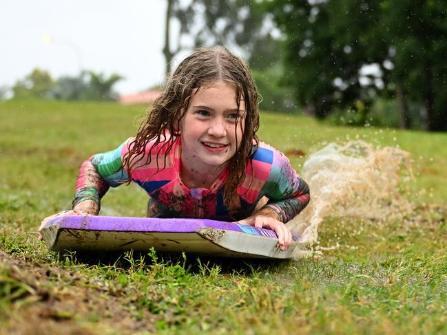 A girl taking advantage of the wet weather and sliding down a mud hill in the suburb of Upper Kedron in Brisbane on Saturday. Picture: Albert Perez/Getty Images