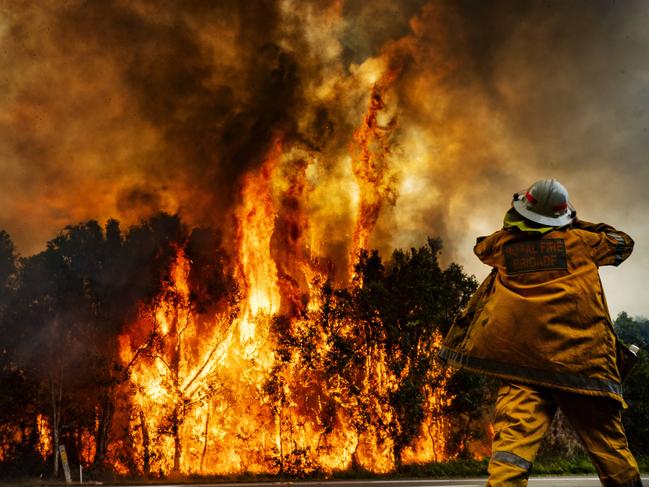 A rural firefighter watches on as as the bushfire blazes east of the David Low Way at at Peregian Beach, residents have been evacuated from Peregian Beach for the second time in a month as another wild bushfire threatened the souther end of town. Photo Lachie Millard