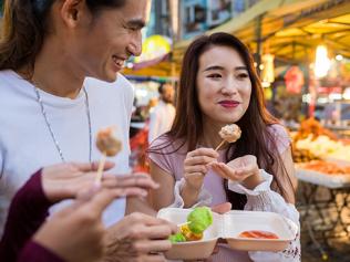 Friends eating local cuisine at a night market. Picture: iStock