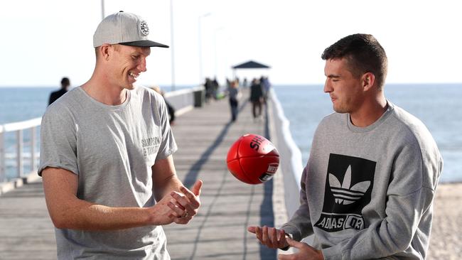 Crows player Sam Jacobs delivers to Port Adelaide recruit Tom Rockliff at Grange Jetty. Picture: Calum Robertson