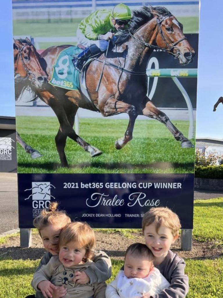 Dean Holland's four children in front of a billboard of their dad winning the Geelong Cup.