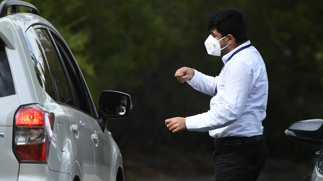 A security guard speaks with people arriving by car at the Anglicare Newmarch House in Western Sydney on Sunday. Picture: AAP