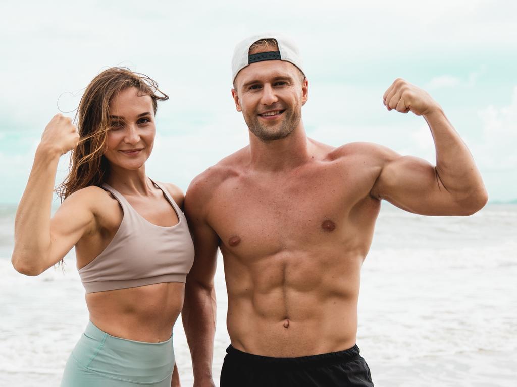 Portraits of Cheerful male and female athlete standing together at seaside. Healthy men and women pose for sexy poses and show off their muscles in the summer day.