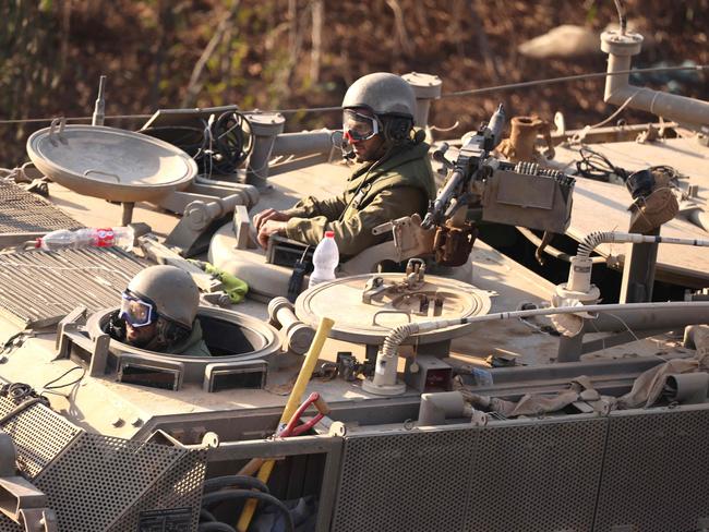 Israeli soldiers gesture as their military convoy moves along the border between Israel and the Gaza Strip. Picture: AFP