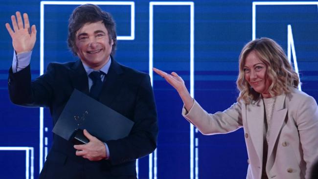 Argentina's President Javier Milei waves from the stage next to Italy's Prime Minister Giorgia Meloni.