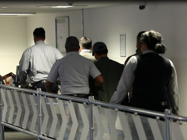 Binjun Xie being escorted through Melbourne Airport. Picture: Supplied