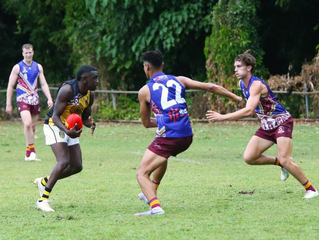 Pictured: Tiger Fitzroy Greenwool dances around Lions defenders Edward Kadlecek and Branden Deslandes. Cairns City Lions v North Cairns Tigers at Holloways Beach. Dreamtime by the Sea. AFL Cairns 2024. Photo: Gyan-Reece Rocha