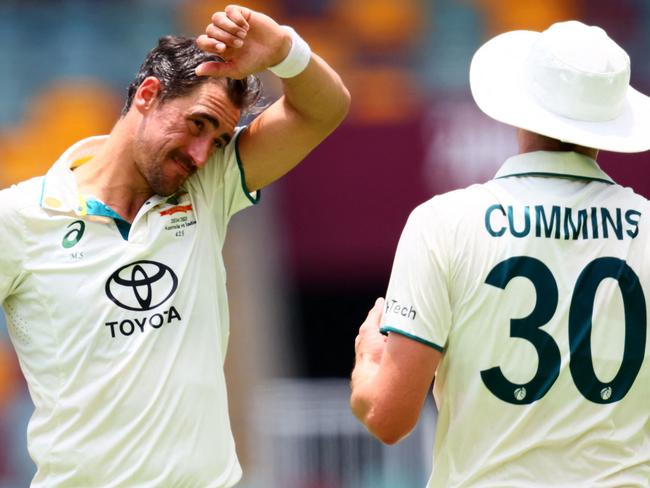 Australia's bowler Mitchell Starc (L) discusses with captain Pat Cummins as he prepares to bowl on day four of the third cricket Test match between Australia and India in Brisbane on December 17, 2024. (Photo by Patrick Hamilton / AFP) / âIMAGE RESTRICTED TO EDITORIAL USE - STRICTLY NO COMMERCIAL USE --