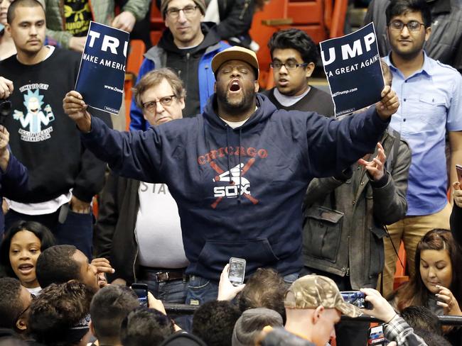 A protester holds up a ripped campaign sign for Donald Trump before the rally on the campus of the University of Illinois in Chicago.