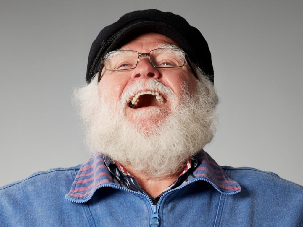 Studio shot of senior man standing with his hands on hips laughing against grey background, laughing dad, generic