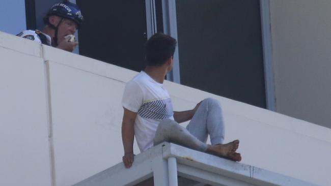 A police rescue officer eats a sandwich as a male sits on the roof 27 stories above a body found in a lane off Brown st Chatswood. Picture: John Grainger.