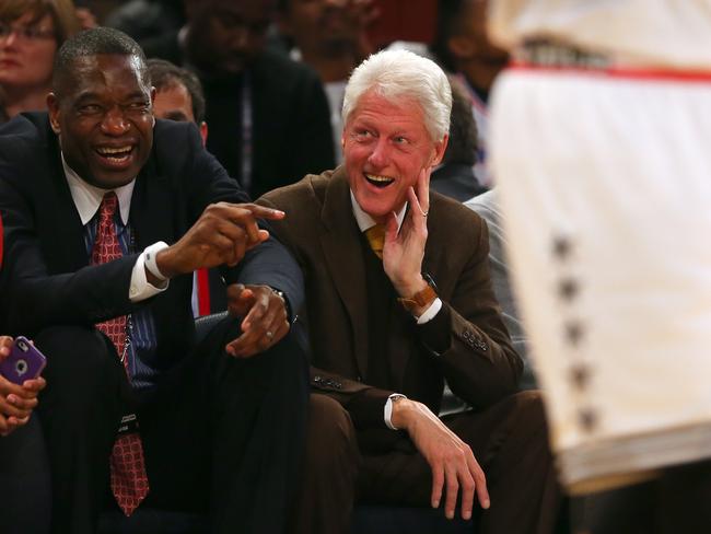 NBA legend Dikembe Mutombo talks with former president Bill Clinton during the game.