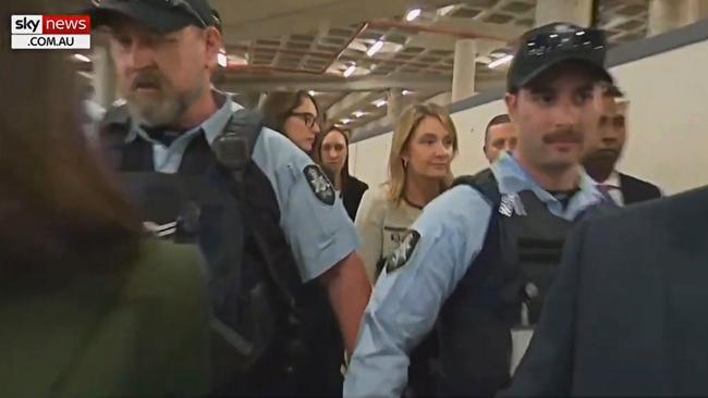 Optus CEO Kelly Bayer Rosmarin walking from the Senate inquiry flanked by police. Picture: television