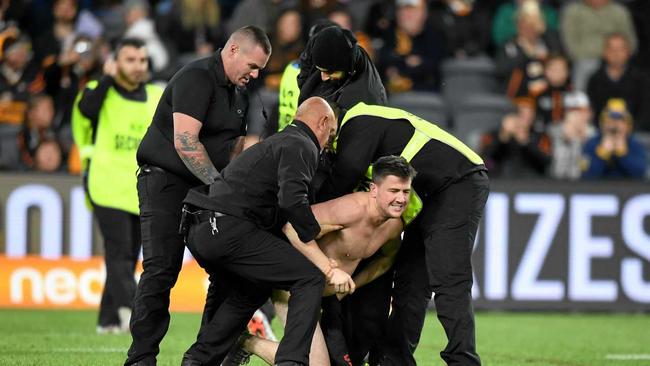 CAUGHT: A streaker is rounded up by security after disrupting the NRL Round 17 clash between the Tigers and Eels. Picture: JOEL CARRETT