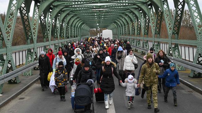 Women and children walk across a bridge into Poland at the Zosin-Ustyluh border crossing in western Ukraine on March 6. Photo: Daniel LEAL / AFP.