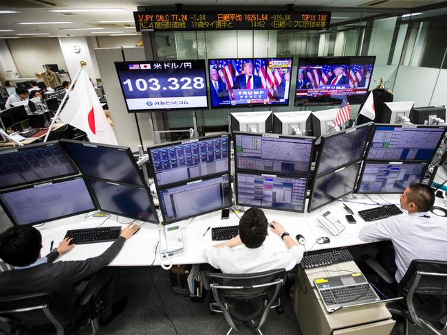 Japanese employees of a foreign exchange trading company work at their terminals in Tokyo as US President-elect Donald Trump is seen on television screens delivering his victory speech. Picture: Behrouz Mehri/AFP