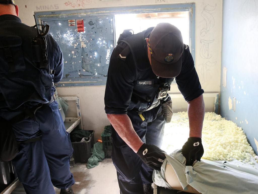 A Corrective Services officers checks the seal on a window for contraband during a raid on cells at Silverwater Jail The officers now wear body cams that record the raids. Picture: Richard Dobson