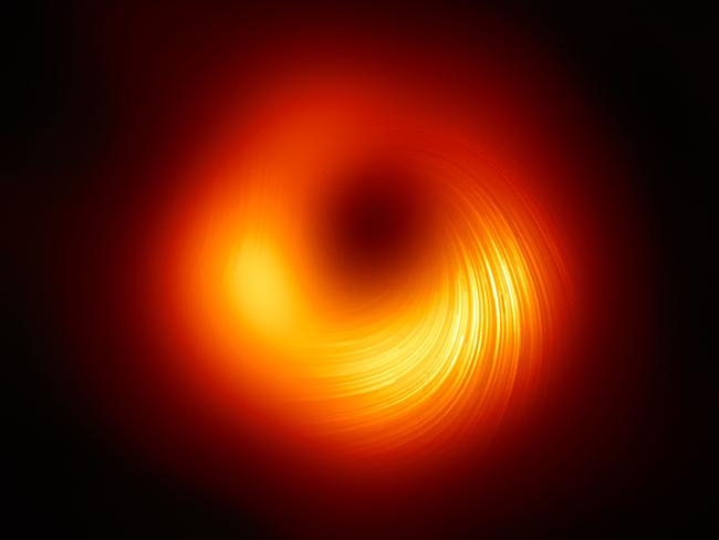 This handout photograph released by The European Southern Observatory on March 24, 2021, shows the polarised view of the black hole in the Messier 87 (M87) galaxy, with lines marking the orientation of polarisation, which is related to the magnetic field around the shadow of the black hole by The Event Horizon Telescope (EHT) collaboration. - The astronomers who gave the world it's first true glimpse of a black hole have produced another landmark image, this time capturing the polarised light swirling around the same star-eating monster's magnetic fields. But it is more than just a pretty picture. Never before has it been possible to measure polarisation -- which causes light waves to vibrate in a single plane -- so close to the edge of a black hole.  The new observations, based on data collected by the Event Horizon Telescope (EHT) in 2017, are key to understanding how a galaxy can project streams of energy thousands of lightyears outward from its core, more than 300 scientists reported Wednesday in a pair of studies. (Photo by Handout / European Southern Observatory / AFP) / RESTRICTED TO EDITORIAL USE - MANDATORY CREDIT "AFP PHOTO /EUROPEAN SOUTHERN OBSERVATORY " - NO MARKETING - NO ADVERTISING CAMPAIGNS - DISTRIBUTED AS A SERVICE TO CLIENTS