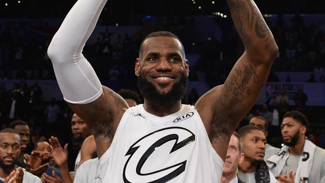 LeBron James hoists the All-Star Game MVP trophy.