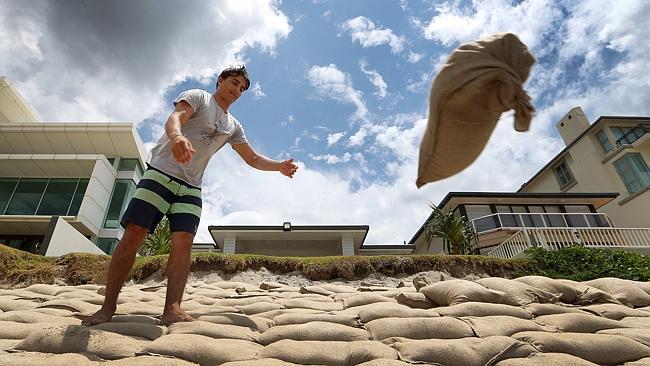 Romain Fesquet throws a sandbag into position in front of beachfront homes at Nobby Beach to help combat storm surges. Pic: Glen