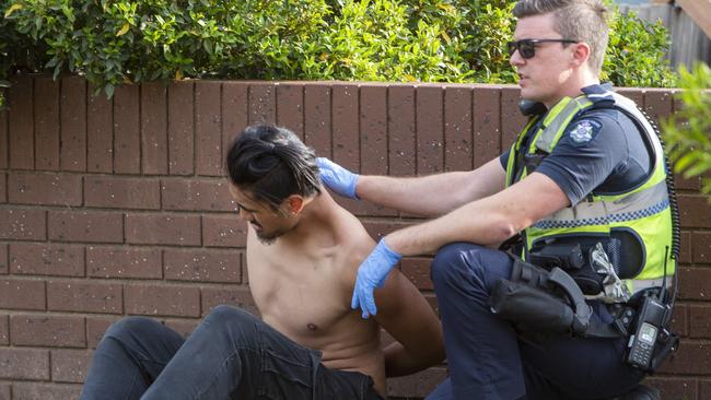 An officer detains a shirtless man on the footpath. Picture: Jay Town