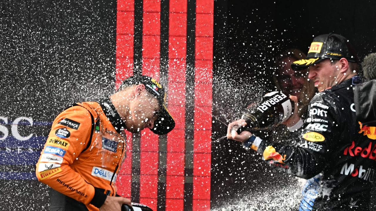 Second-placed McLaren's British driver Lando Norris (L) and race winner Red Bull Racing's Dutch driver Max Verstappen spray champagne on the podium.