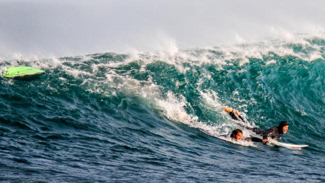 Alejandro Travaglini, left, is helped to safety by a fellow surfer after being bitten by a shark near Gracetown, WA, yesterday. Picture: Peter Jovic