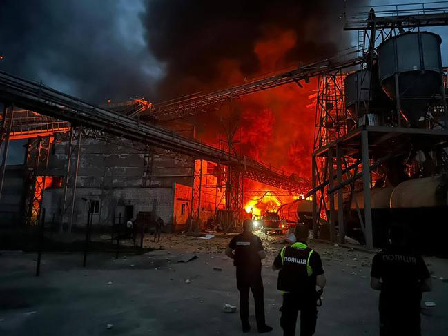 Ukrainian law enforcement officers stand next to the burning industrial facility following a missile strike in the village of Hoholeve, Poltava region. Picture: AFP